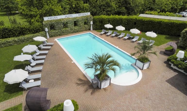 Outdoor pool with sun loungers and umbrellas at Savoia Hotel Regency.