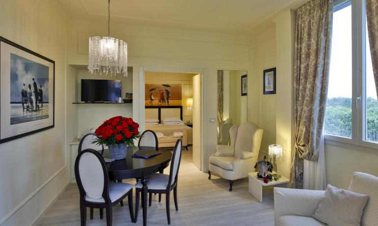 Elegant living room with table, flowers, and bedroom view.