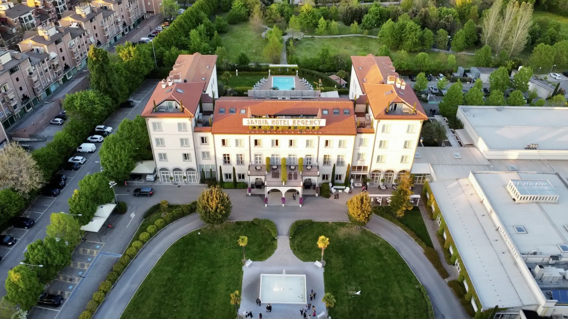 Aerial view of Savoia Hotel Regency with gardens and pool.
