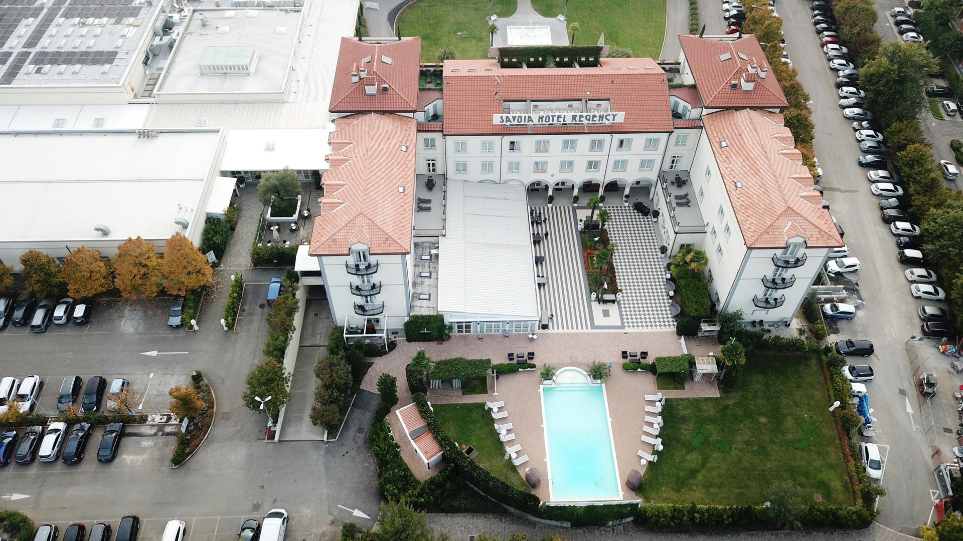 Aerial view of Savoia Hotel Regency with pool, parking, and garden.