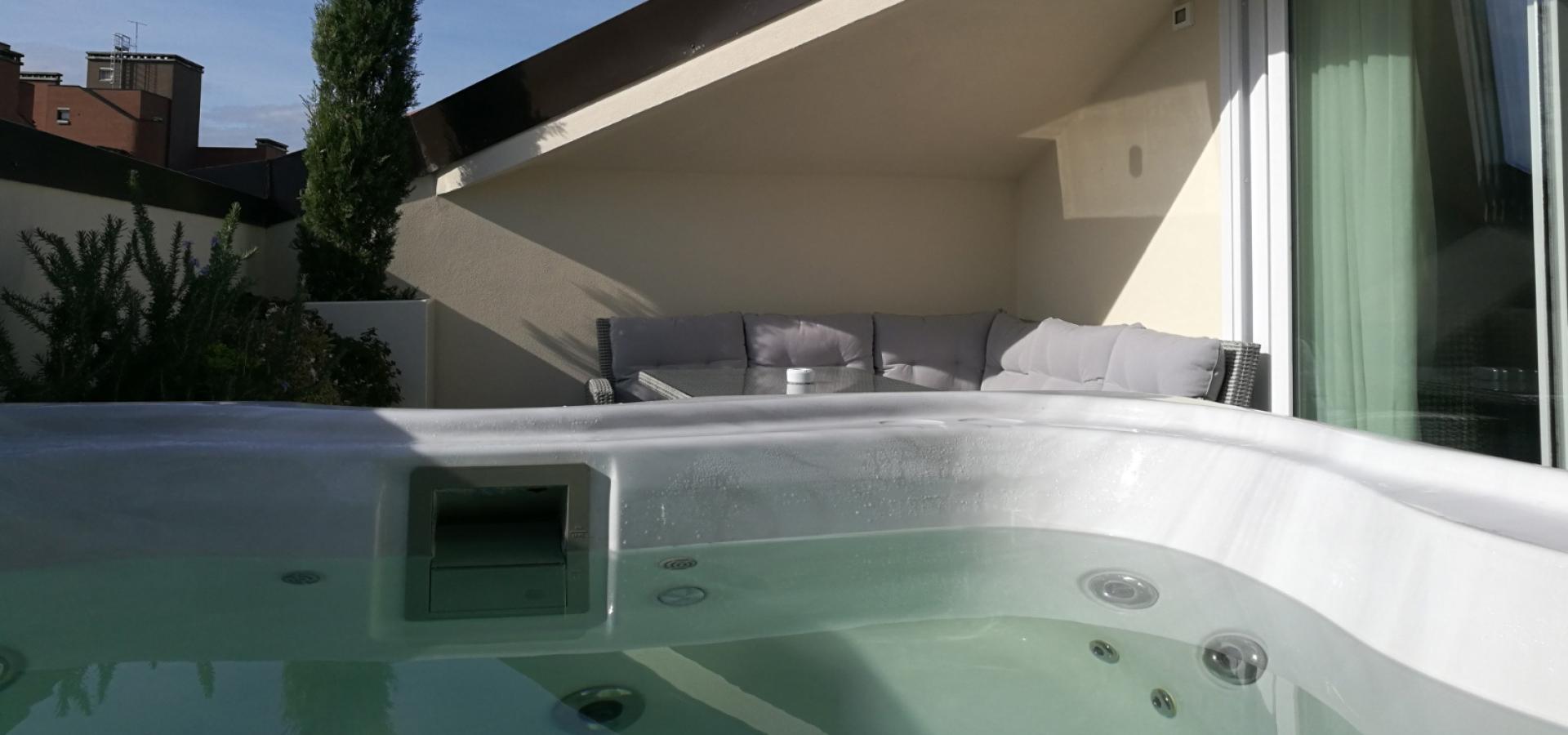 Terrace with hot tub and sofa under a slanted roof.