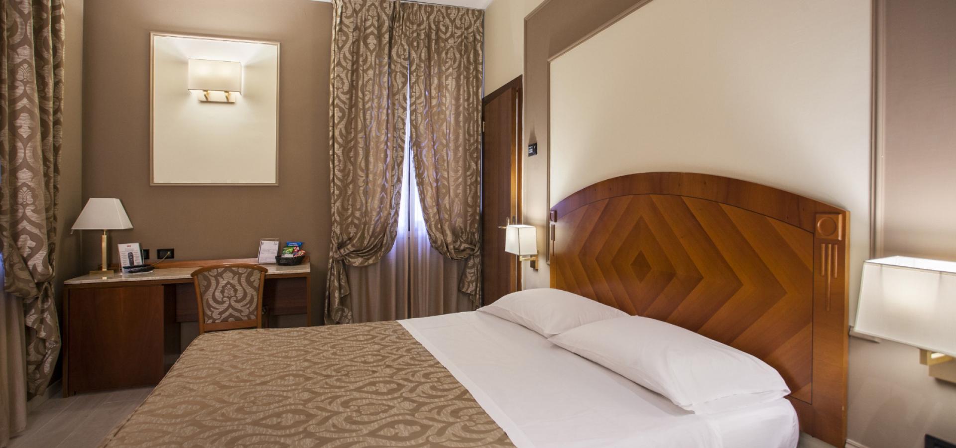 Elegant hotel room with a double bed and a desk.