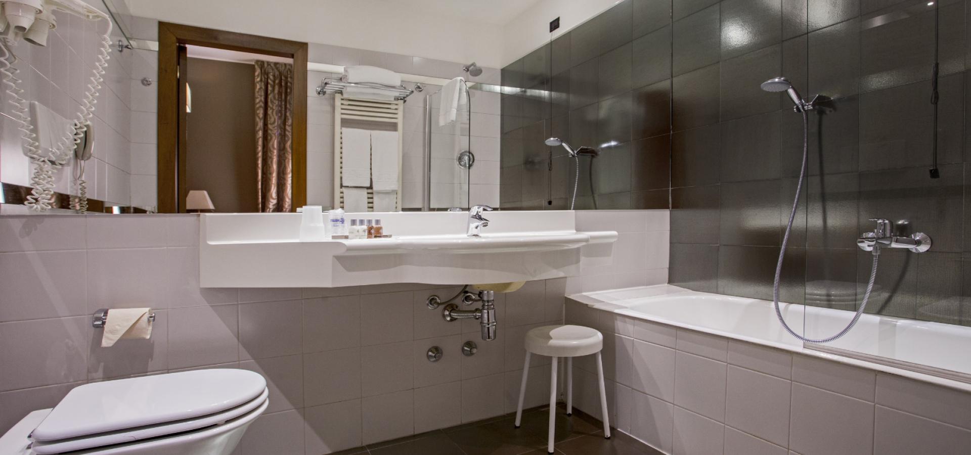 Modern bathroom with bathtub, sink, mirror, and hairdryer.