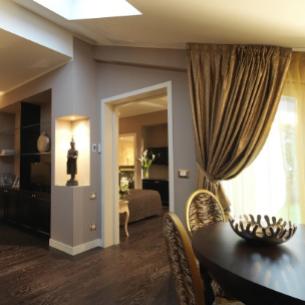 Appartamento moderno con arredi eleganti, pavimenti in legno scuro e ampie finestre.