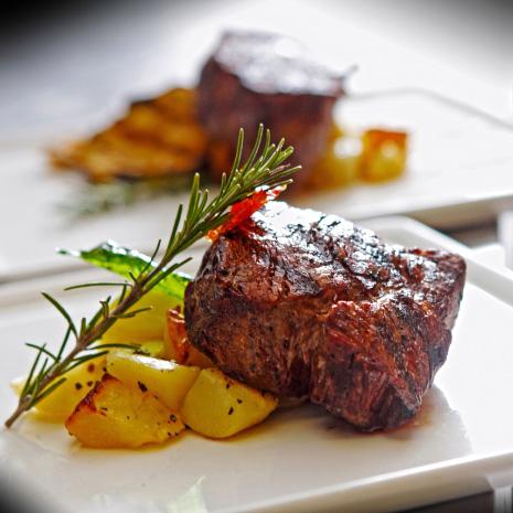 Beef fillet with roasted potatoes and a sprig of rosemary.