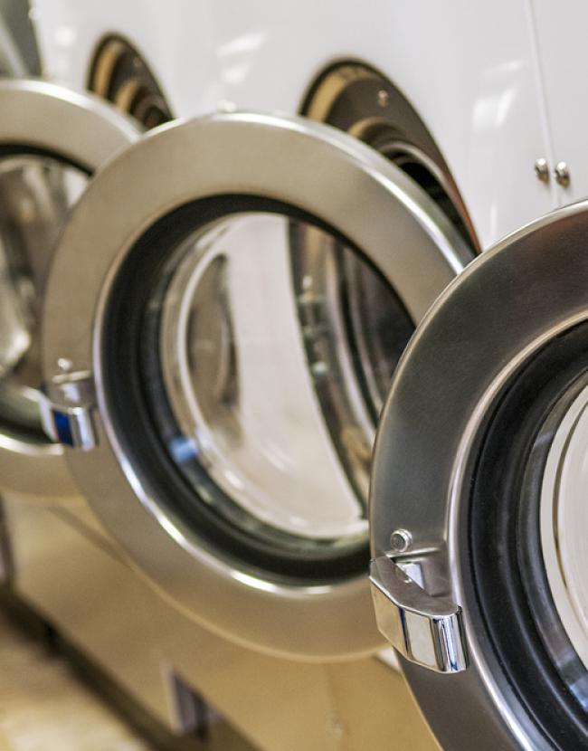 Industrial washing machines in a row, ready for use in a laundry facility.