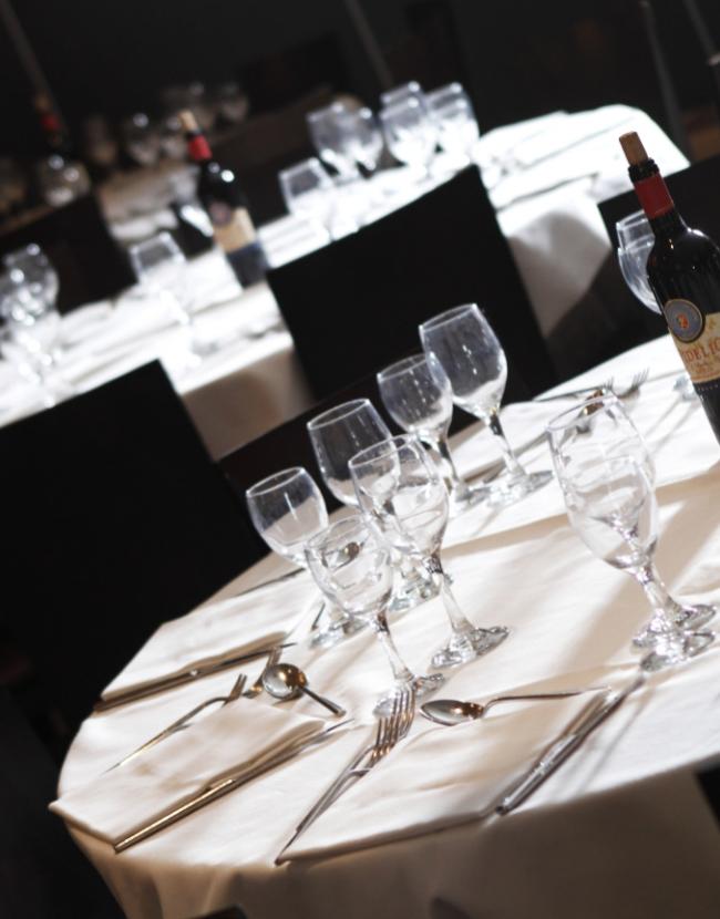 Tavoli apparecchiati con bicchieri e posate, pronti per una cena elegante.