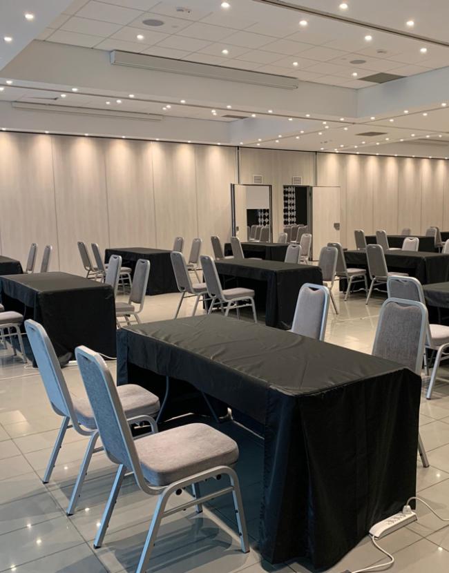 Sala conferenze con tavoli e sedie, pronta per un evento o riunione.