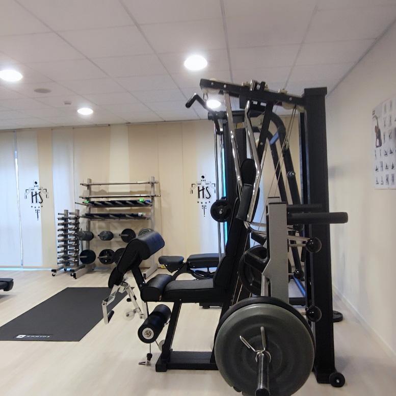 Gym with multifunction machines, free weights, and workout equipment.
