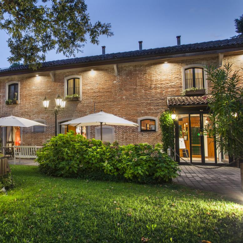 Charming brick building with garden and umbrellas, illuminated in the evening.