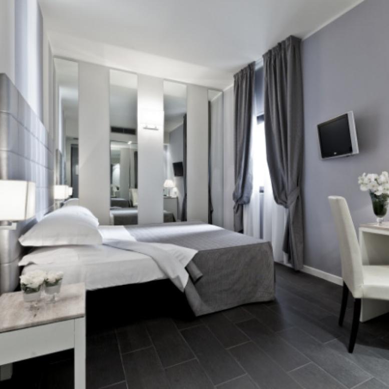 Modern room with double bed, mirrors, wall-mounted TV, and desk.