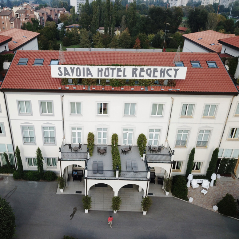 Aerial view of Savoia Hotel Regency with red roof and garden.