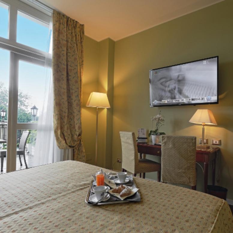 Hotel room with balcony, TV, and breakfast on the table.