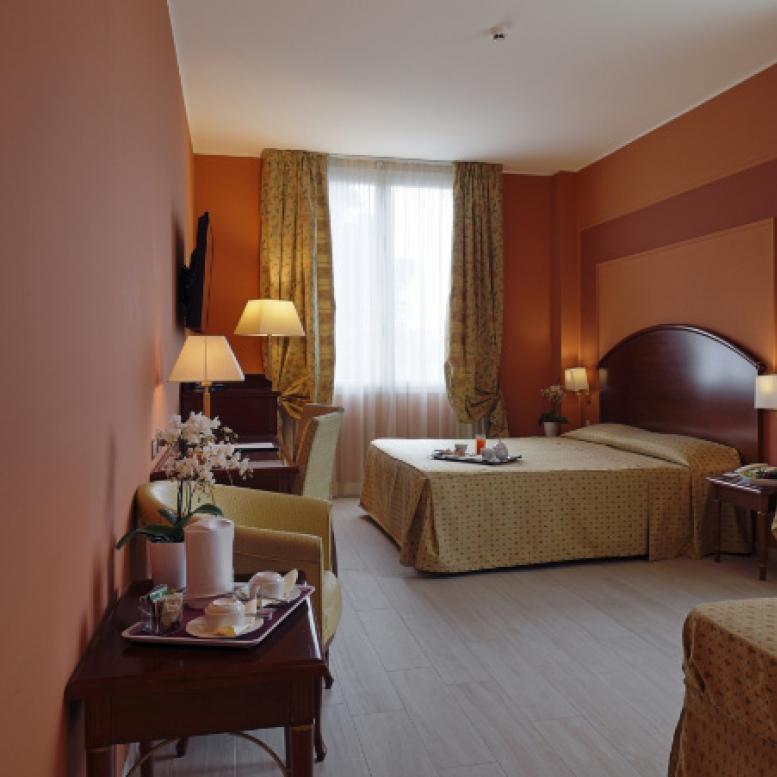 Hotel room with double bed, elegant furnishings, and natural light.